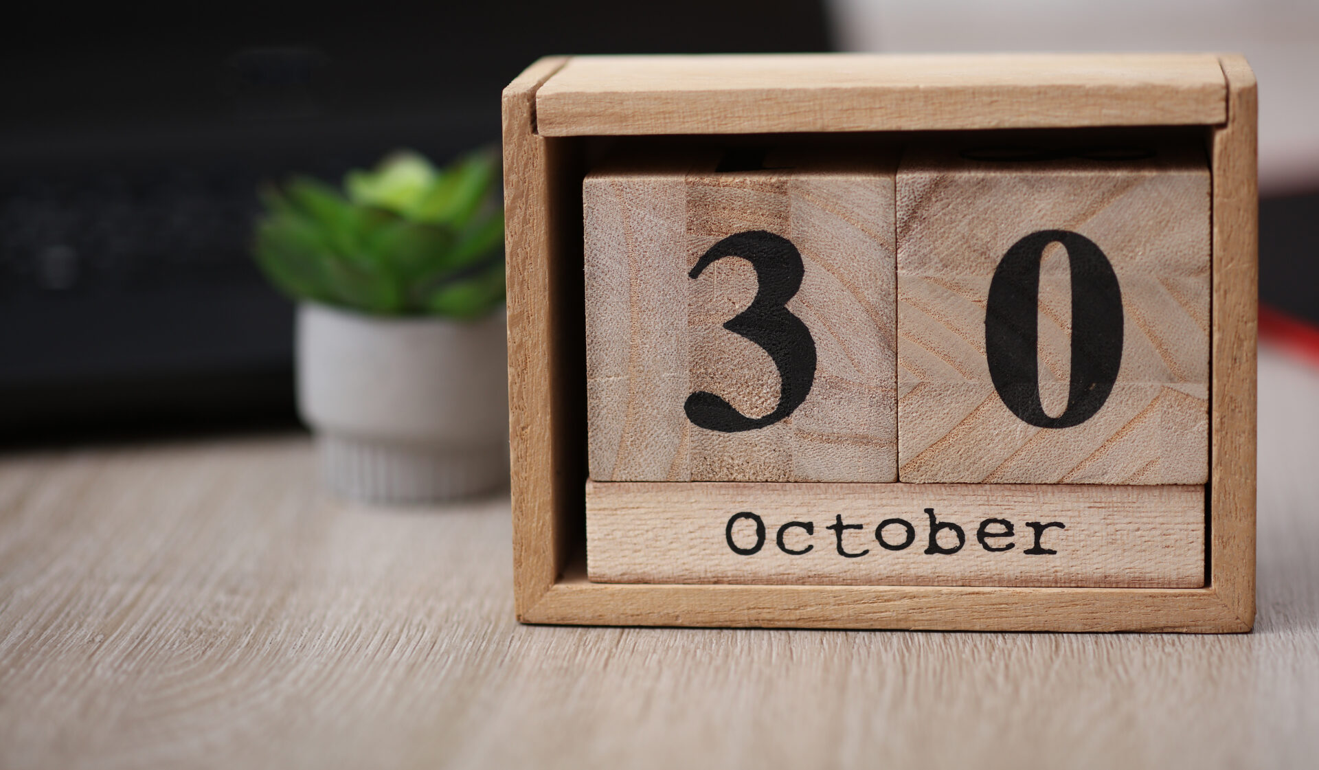 Wooden calendar with the date October 30 on desktop with laptop