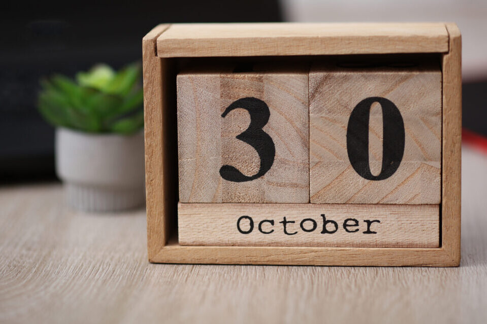 Wooden calendar with the date October 30 on desktop with laptop